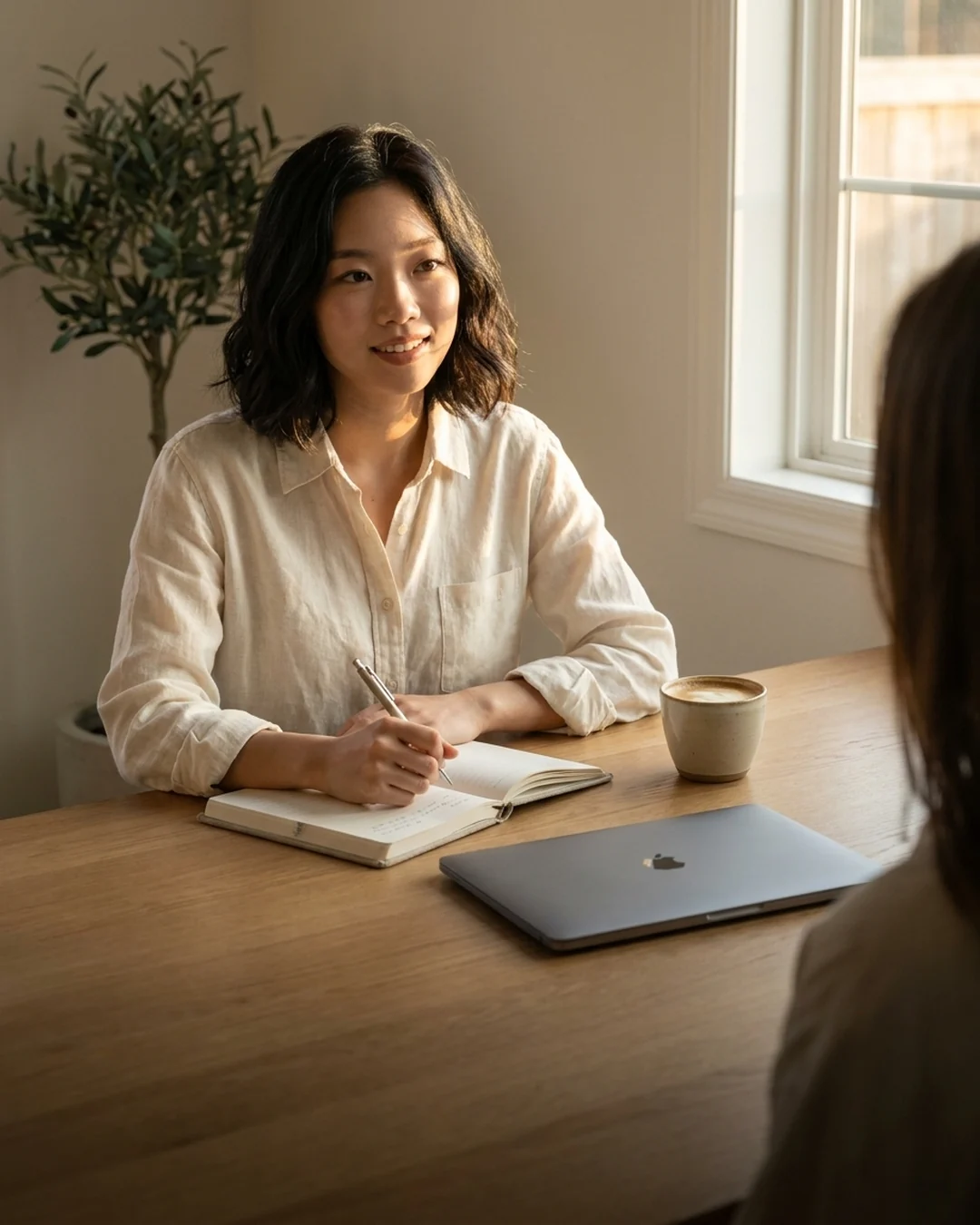 Squarespace designer taking notes during a discovery conversation in a sunlit studio