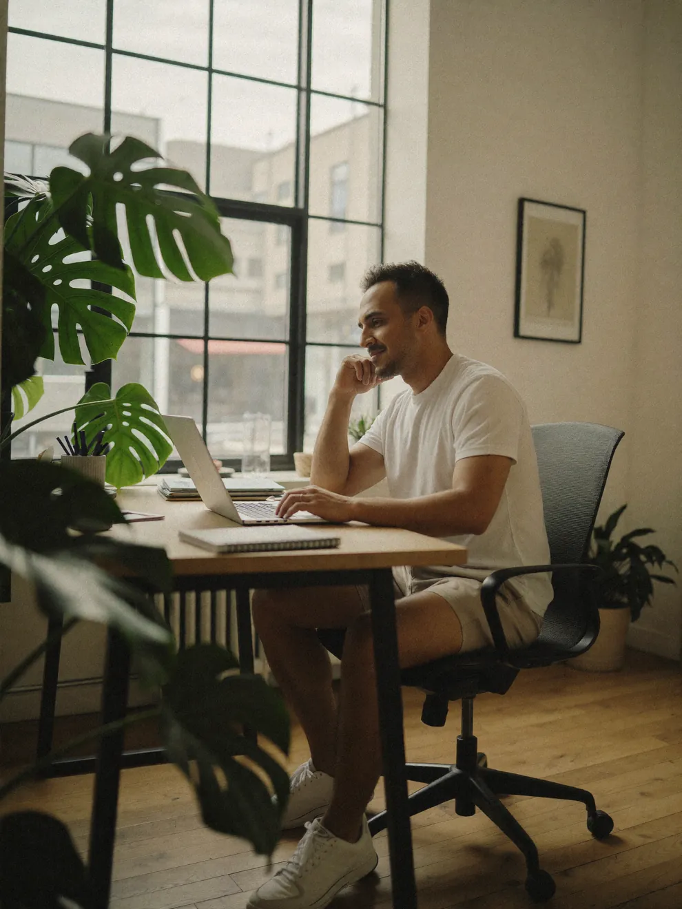 Rahim, Squarespace designer and founder of SQSP, working on a laptop at his sunlit studio desk