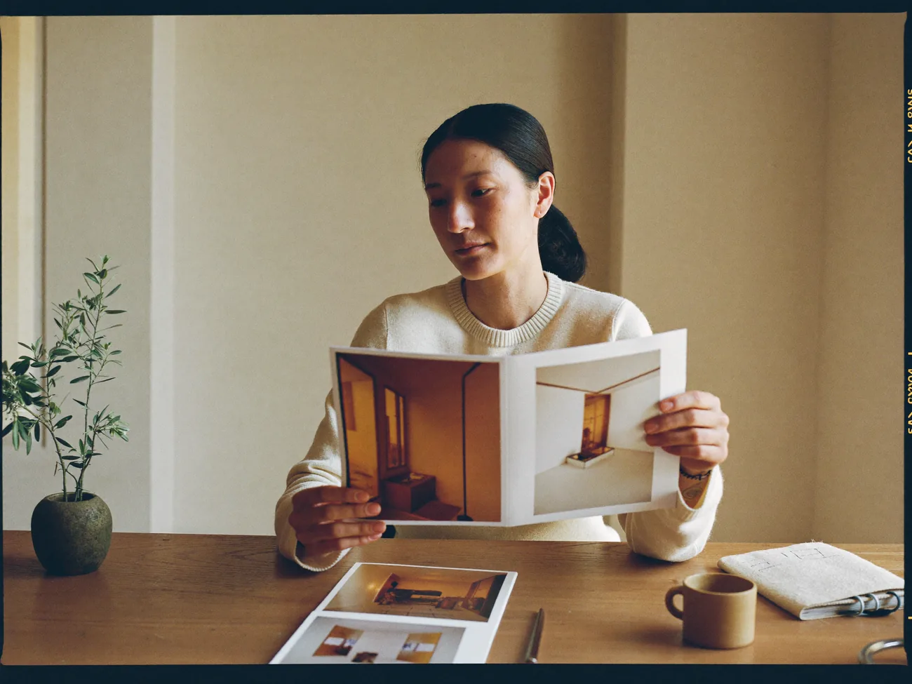 A Squarespace designer reviewing portfolio prints at a warm studio desk