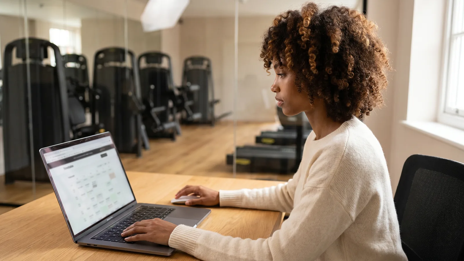 A gym owner reviewing her club's website on a laptop in the club office