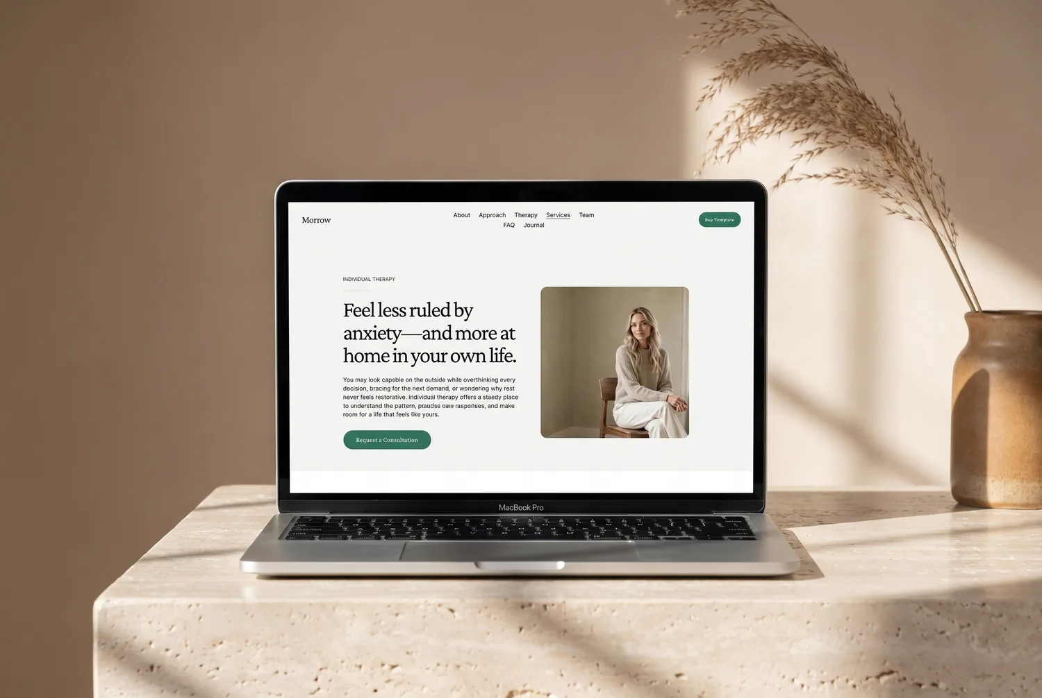 Morrow template individual-therapy specialism page on a laptop — ‘Feel less ruled by anxiety’ with a practitioner portrait