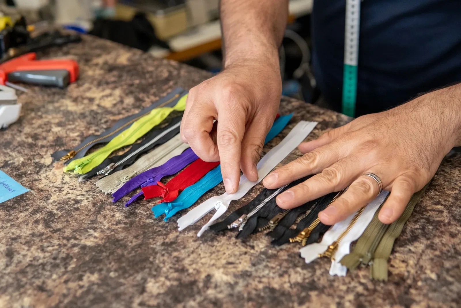 Eddy selecting from a row of colour-matched zips on the workbench during an alteration