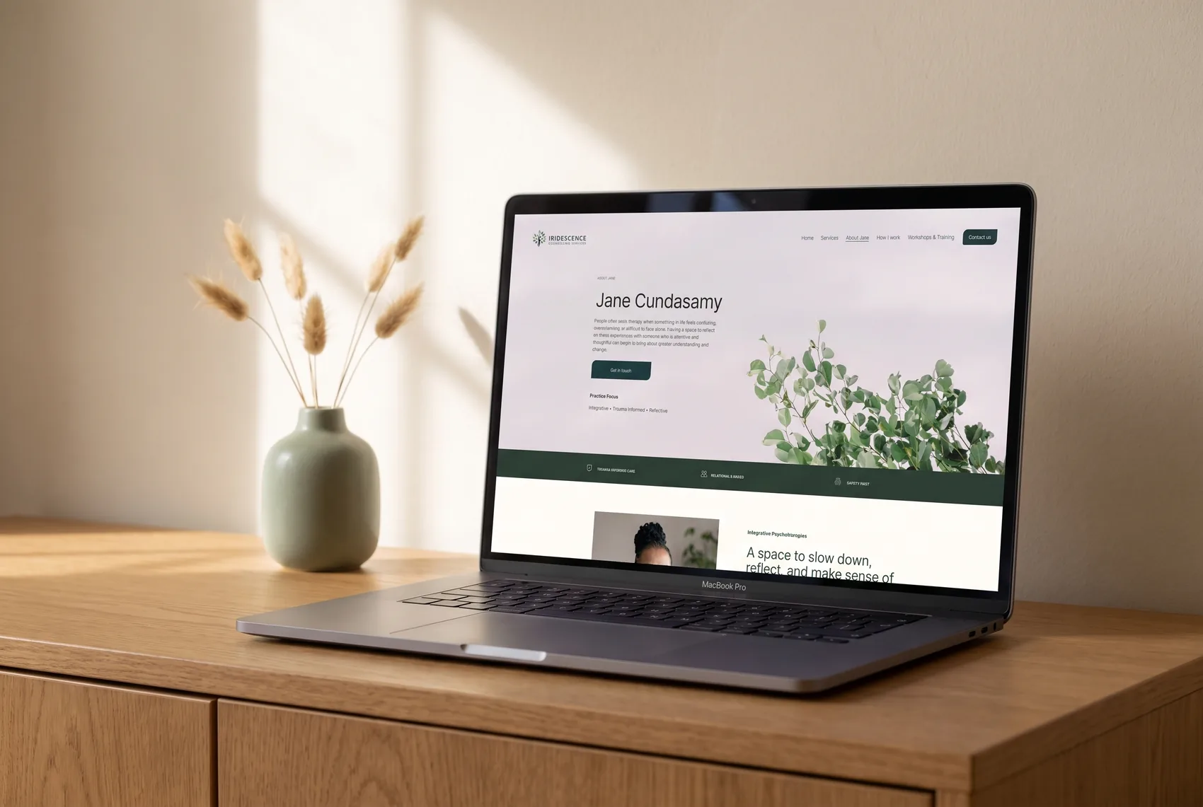 The About Jane page introducing psychotherapist Jane Cundasamy, shown on a MacBook beside a sage ceramic vase
